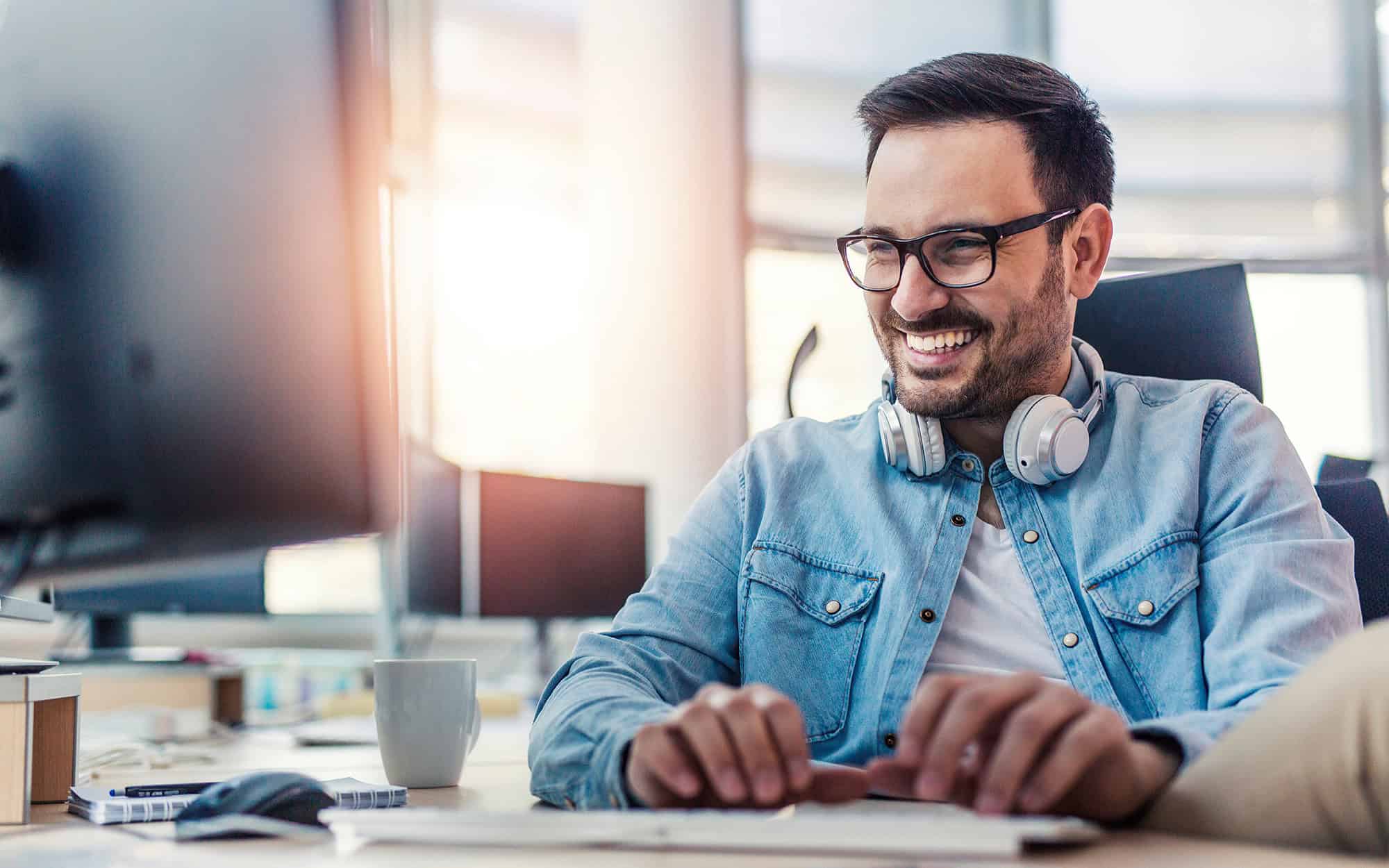 Front View Of Happy Smiling Man In Office On Computer