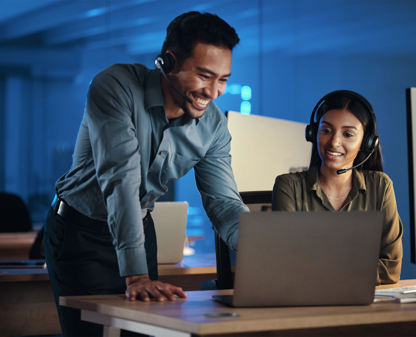 Front View Of Two People With Headsets At Computer