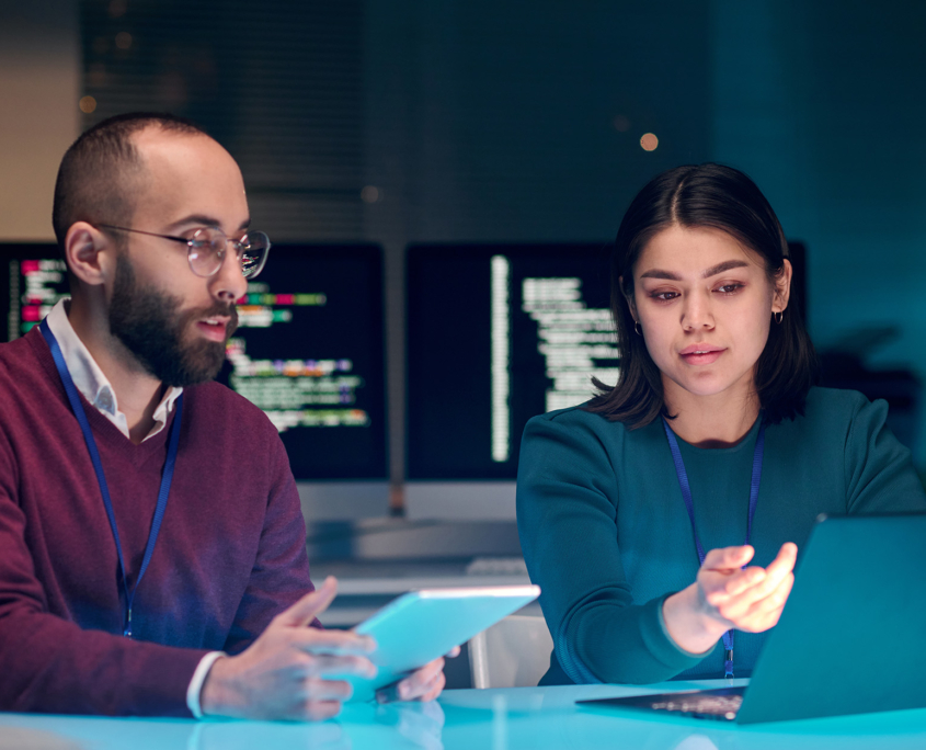 Portrait Of Young Woman As Female It Security Expert Using Laptop With Male Colleague